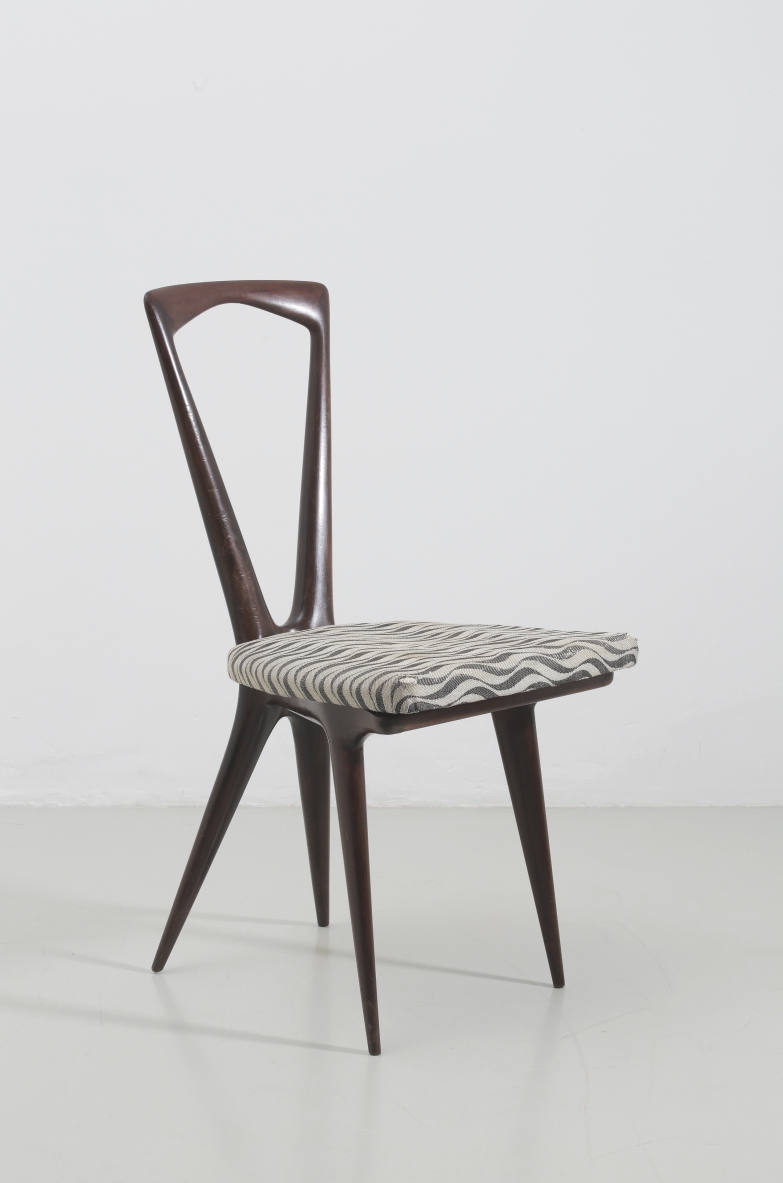 Angled view of a Gianni Vigorelli modernist chair in dark mahogany, with a tall asymmetrical open backrest, geometric patterned upholstered seat and tapered legs.