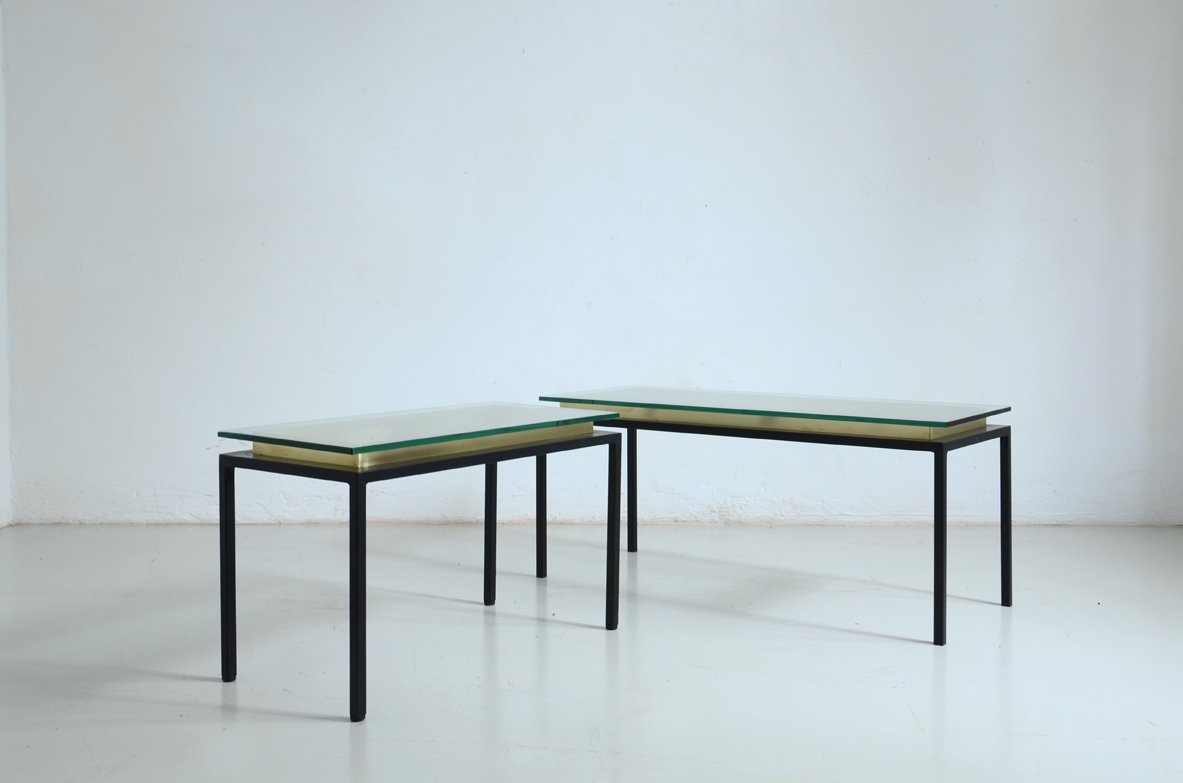 Coppia di tavoli bassi con struttura in metallo tinta di nero satinato, piano in cristallo che poggia su una cornice di ottone.