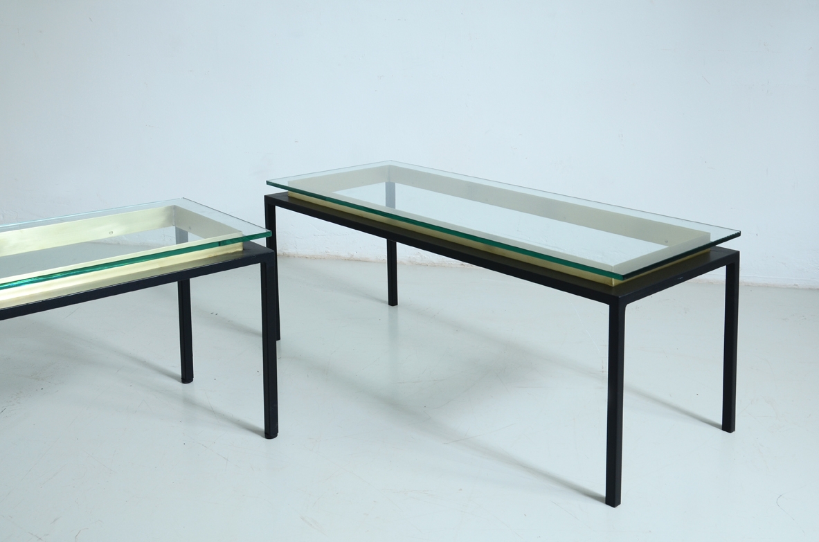 Coppia di tavoli bassi con struttura in metallo tinta di nero satinato, piano in cristallo che poggia su una cornice di ottone.