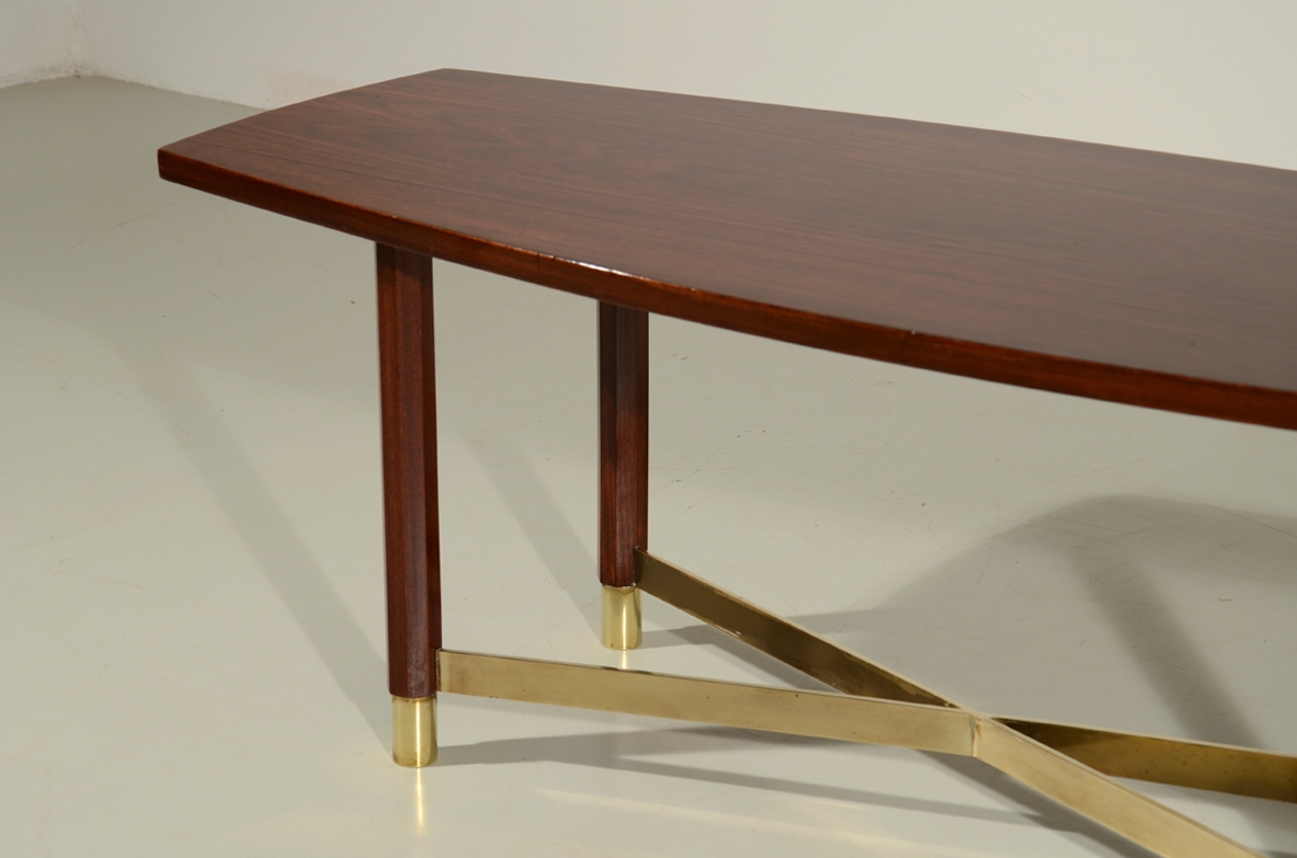Piccolo elegante tavolino in palissandro con importante crociera alla base e piano leggermente curvato. Manifattura Italiana 1950ca.