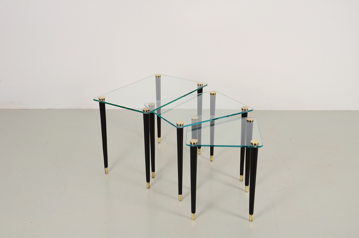Set di tre piccoli tavolini da caffè con piano in vetro di grande spessore e gambe coniche con puntali in ottone. Manifattura Italiana 1960ca.