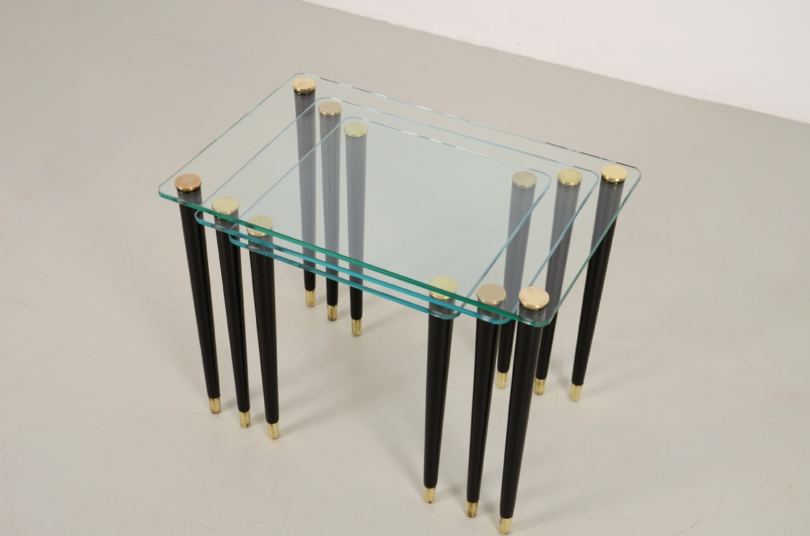 Set di tre piccoli tavolini da caffè con piano in vetro di grande spessore e gambe coniche con puntali in ottone. Manifattura Italiana 1960ca.