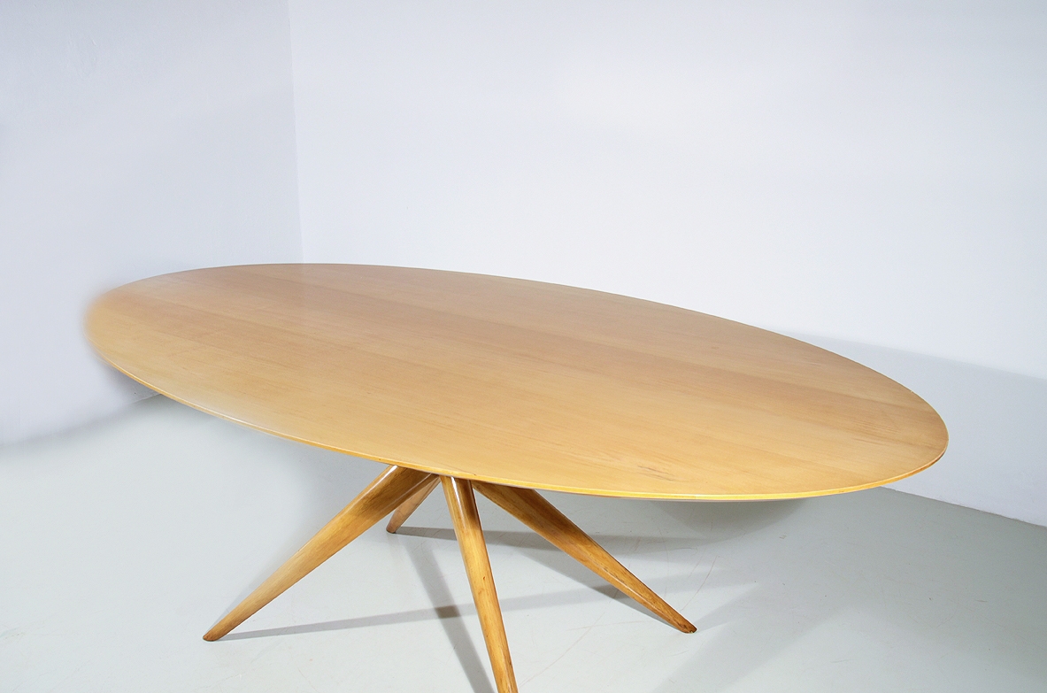 Grande tavolo ovale in acero biondo con gamba centrale a quattro razze. Manifattura Italiana 1950ca.