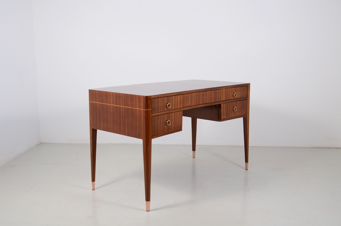 Scrivania a cinque cassetti in noce e acero con gambe tronco piramidali e puntali in ottone. Manifattura Italiana 1950ca.