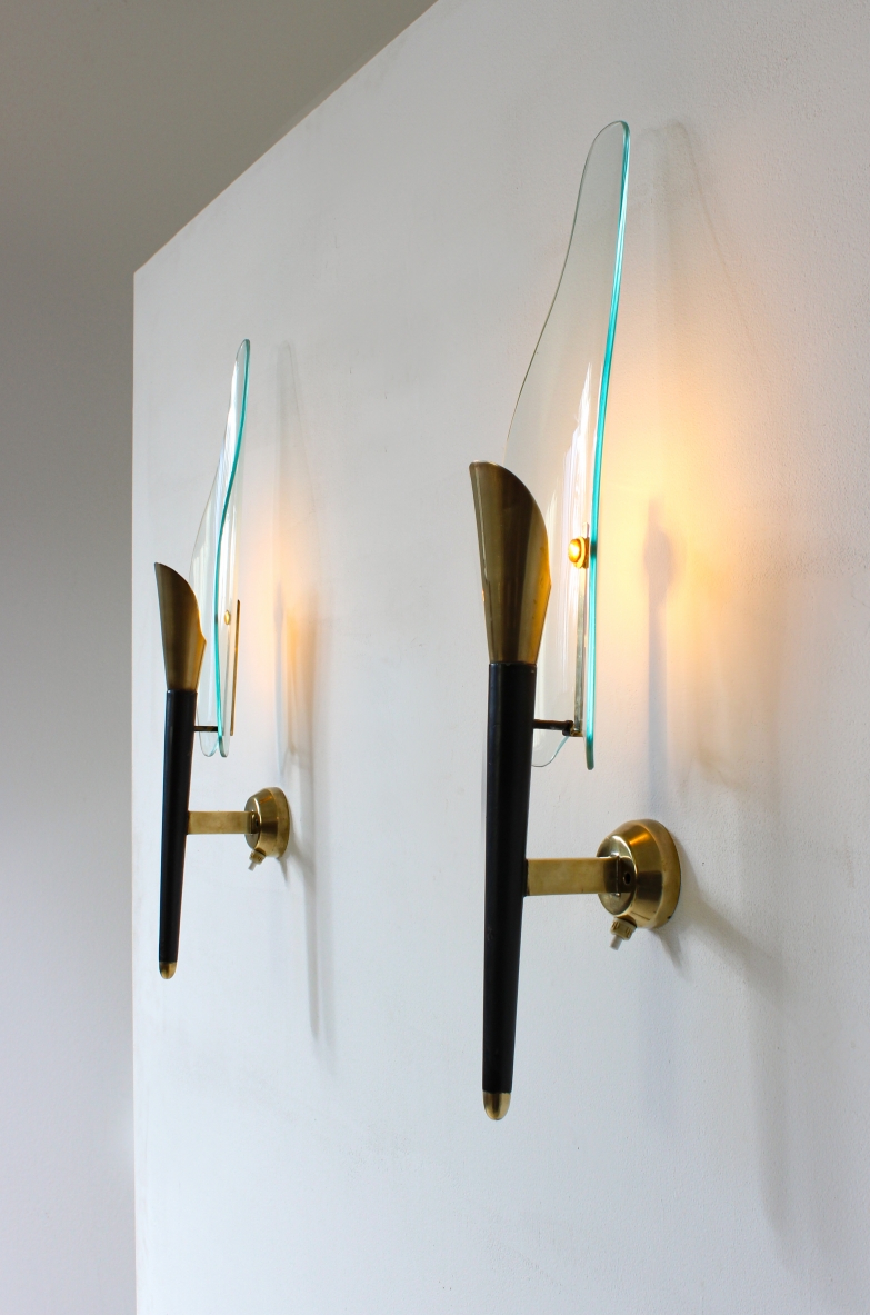 Pair of Crystal Art wall lamps, featuring vertical dark wood and brass structures, elongated transparent bevelled glass shades and circular brass wall mounts, front view.