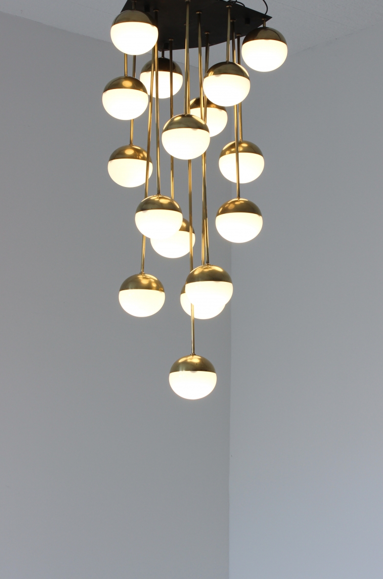 Large Stilnovo Milano chandelier, featuring 18 illuminated white opaline glass globes, brass cups and suspension rods arranged at varying heights, with a dark metal circular ceiling plate.