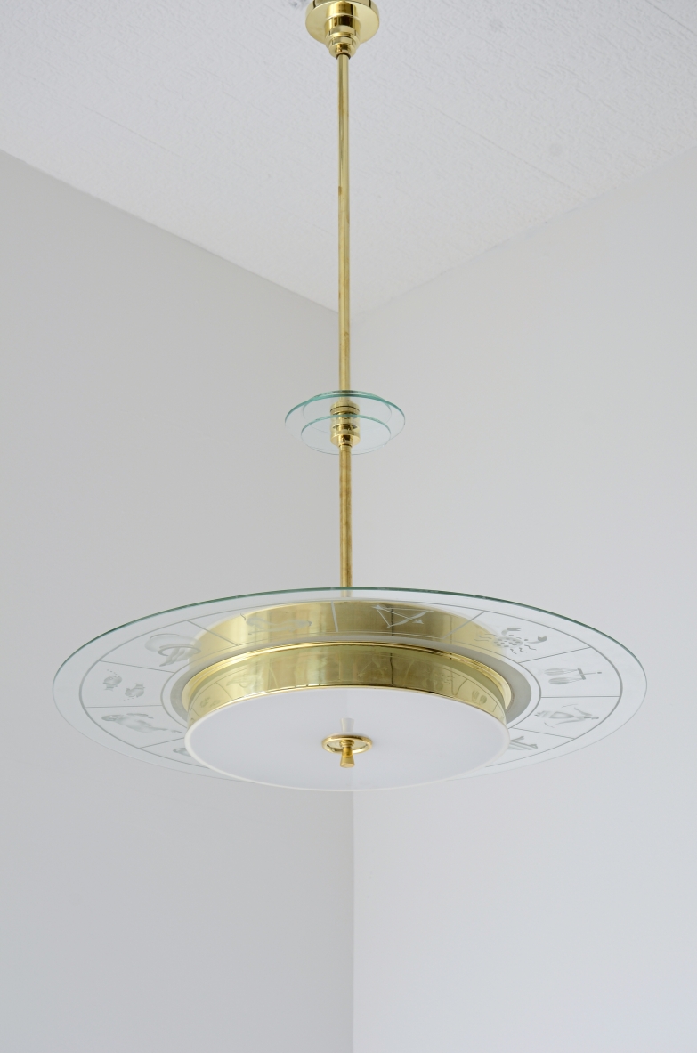 Large brass chandelier with beveled glass decorated with zodiac designs and two milky white glasses. Brass stem with three transparent bevelled glass discs.