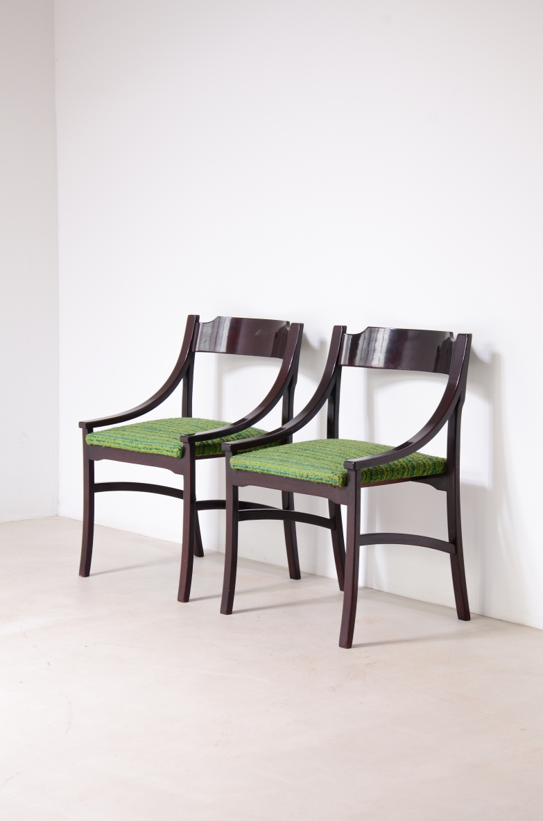 Angled view of two Melchiorre Bega chairs in dark wood, with open backs, curved upper rails, green upholstered seats and tapered legs.