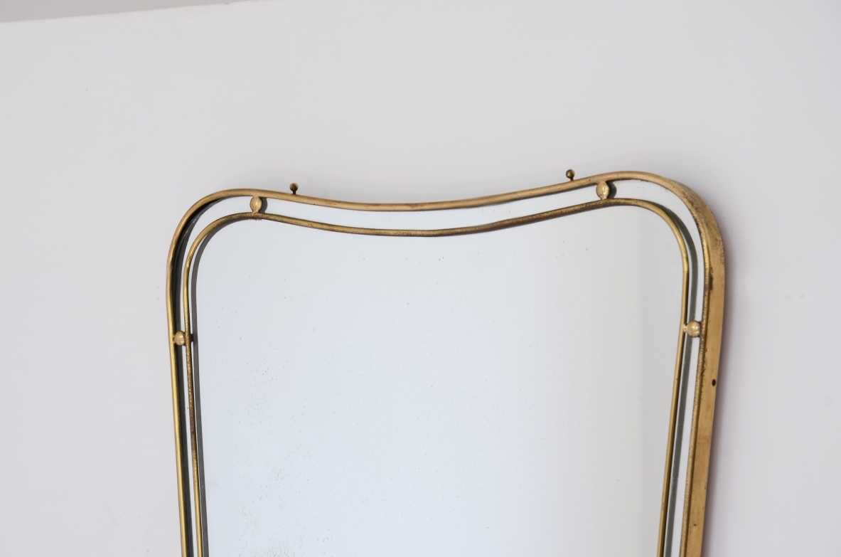 Specchiera con cornice in ottone sagomato a doppio profilo con distanziatori a sfera.  Manifattura italiana 1950ca.