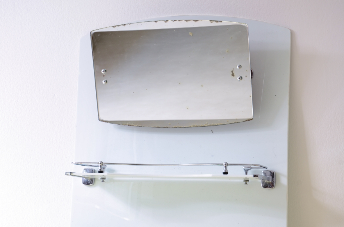 Specchio da bagno in opaline bianca con specchio basculante, mensola e porta saponette in metallo cromato.  Manifattura francese, 1930ca. Specchio da bagno in opaline bianca con specchio basculante, mensola e porta saponette in metallo cromato.  Manifattura francese, 1930ca.