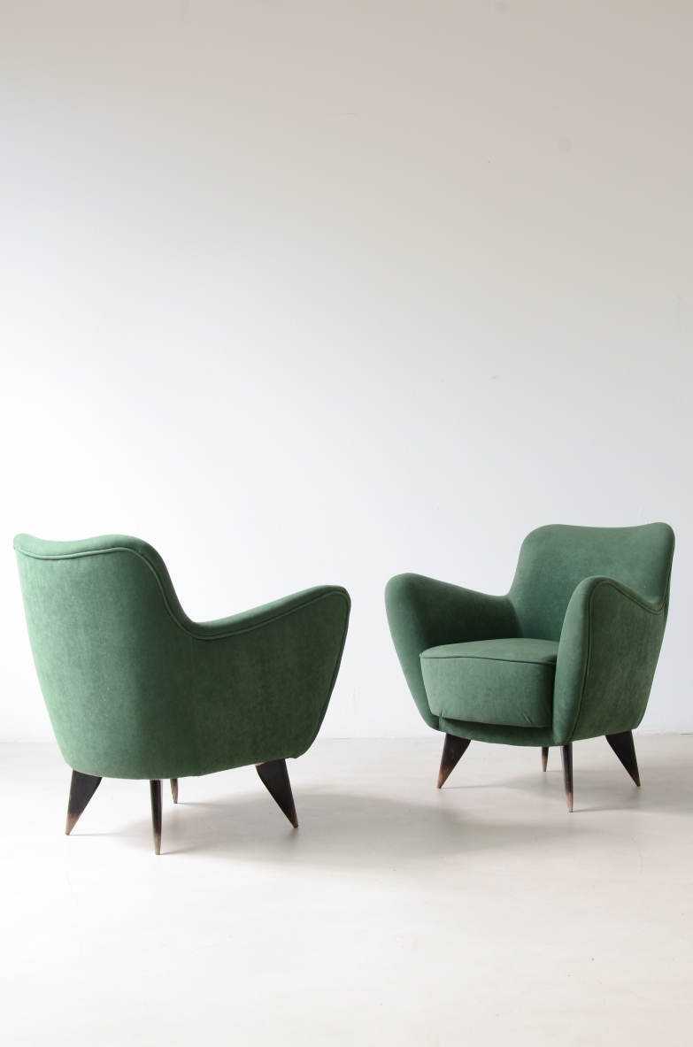 Pair of Gio Ponti armchairs designed for the Conte Grande ocean liner, upholstered in green velvet, with enveloping backrests, curved armrests and tapered dark wooden legs, shown from front and rear angles.