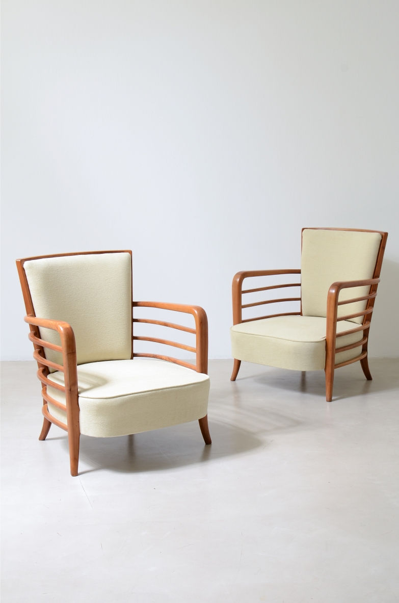 Two armchairs attributed to Paolo Buffa, with curved cherrywood frames, horizontal slatted armrests, rectangular upholstered backrests and light-colored fabric seats.