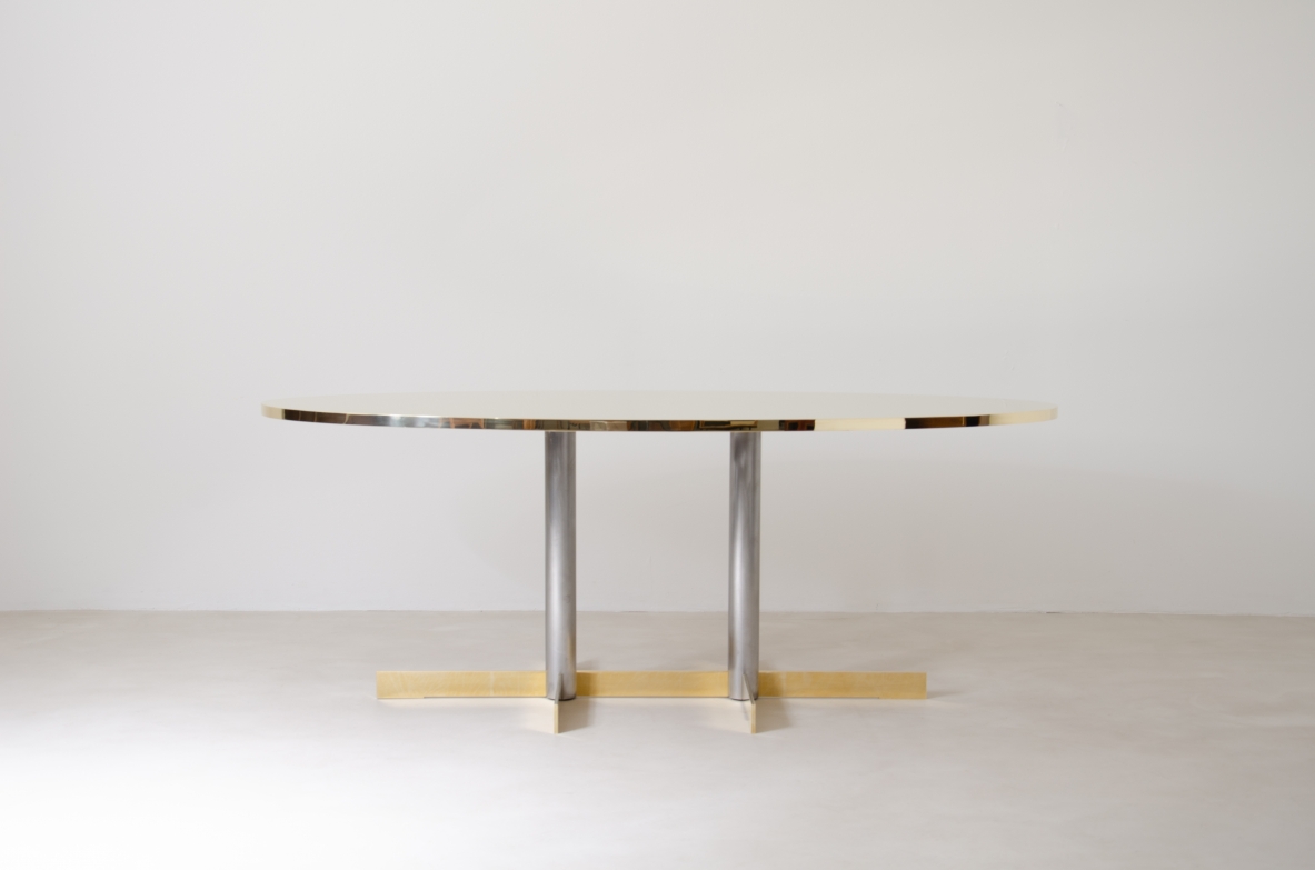 Contemporary oval dining table designed by Officina Antiquaria, featuring a slim brass top, two vertical metal supports and horizontal brass base, front view.