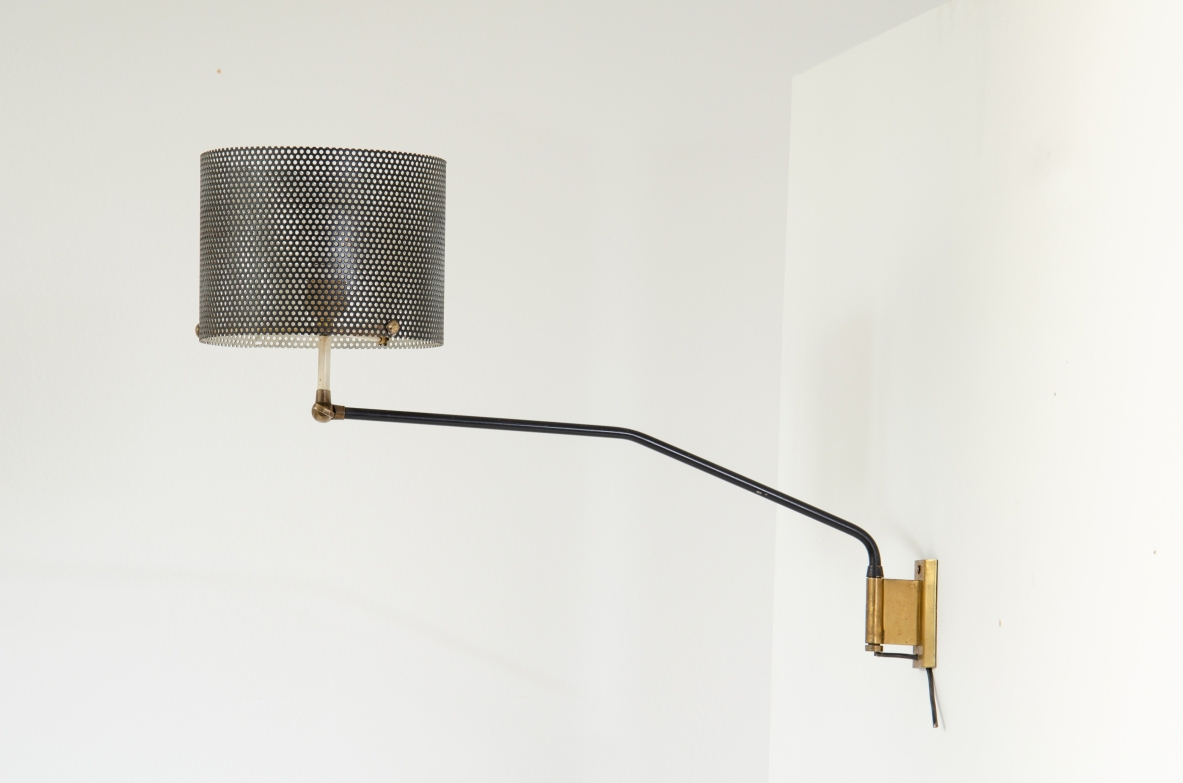 Stilnovo, lampada da parete con braccio tubolare e paralume in rete metallica. Dettagli in ottone. 1950ca. Etichetta del produttore.