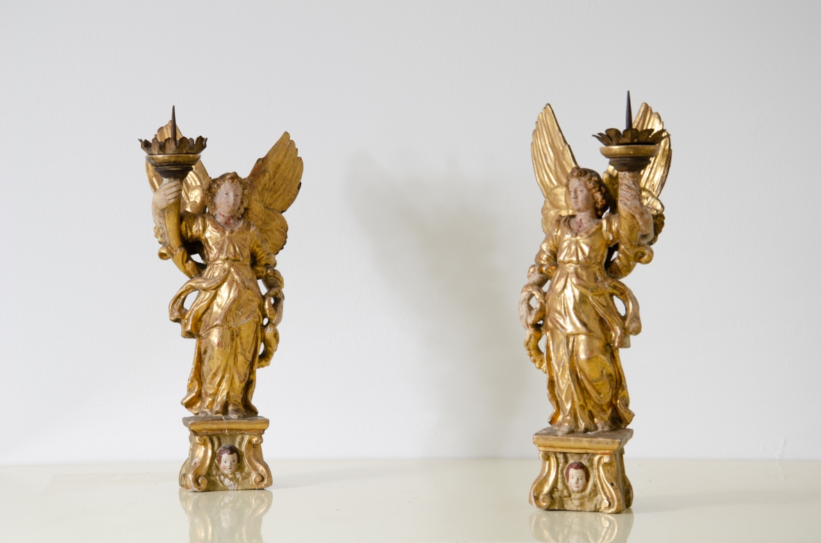 Coppia di angeli in legno laccato e dorato che reggono una cornucopia con corona in metallo dorato.   Italia centrale, epoca Barocco, seconda metà del XVII secolo.