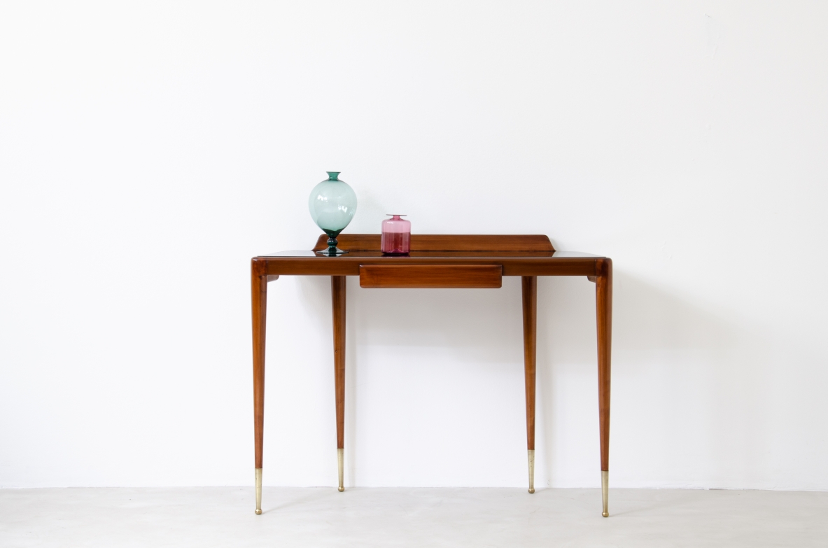 Elegant console table with thin legs in blond walnut and long brass tips. Central drawer and top in black opaline glass.  Italian manufacture, 1950s.