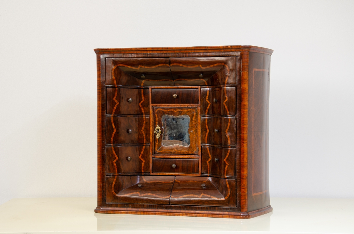 Genoese cabinetry, c. 1750, coin cabinet in violet wood threaded in rose wood with wavy front, central aedicule with shaped door and central mirror.