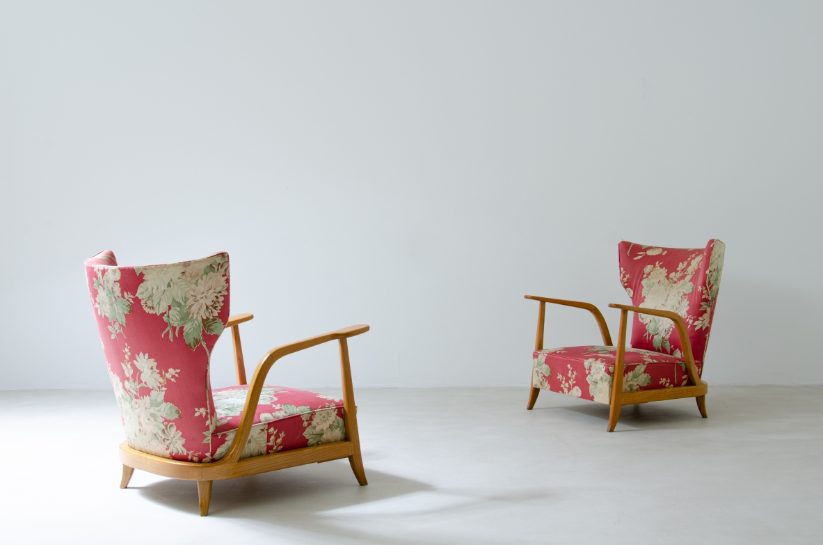 Pair of Enrico Ciuti armchairs with light ash wood frames, curved armrests, tapered legs and upholstered seats and backrests in red and ivory floral-patterned fabric.