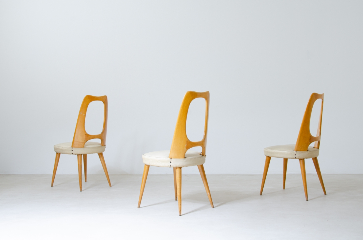 Group view of three Vittorio Dassi chairs in light maple wood, with tall sculptural open oval backrests, light fabric-upholstered seats and tapered legs.
