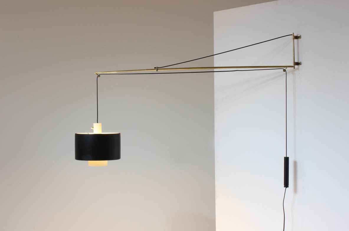 Rare Gaetano Scolari model 2061 wall lamp for Stilnovo, 1954, featuring a long telescopic brass arm, pulley and counterweight system, cylindrical black painted metal shade, side view.