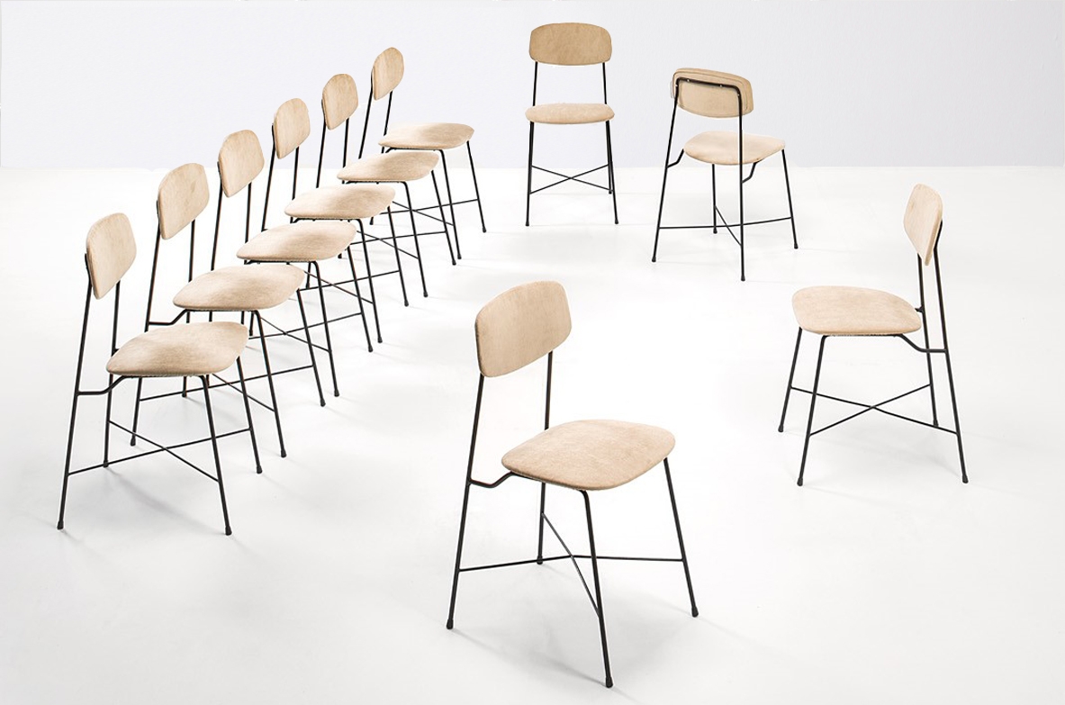 Group view of ten Georges Coslin chairs by Faram arranged in different positions, with slender iron frames and beige fabric-upholstered seats and backrests.