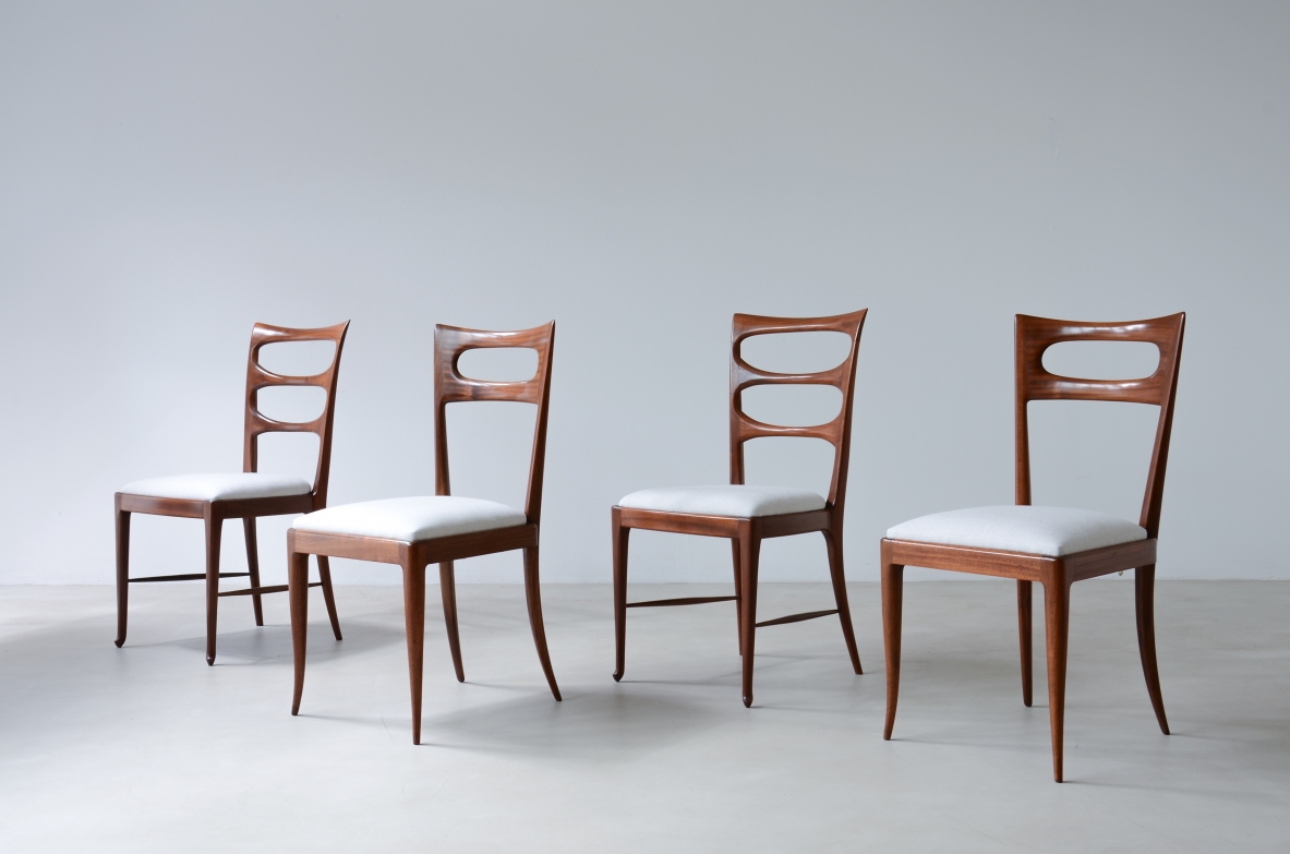 Group view of four Paolo Buffa wooden chairs featuring two variations of open backrests and light-colored upholstered seats.