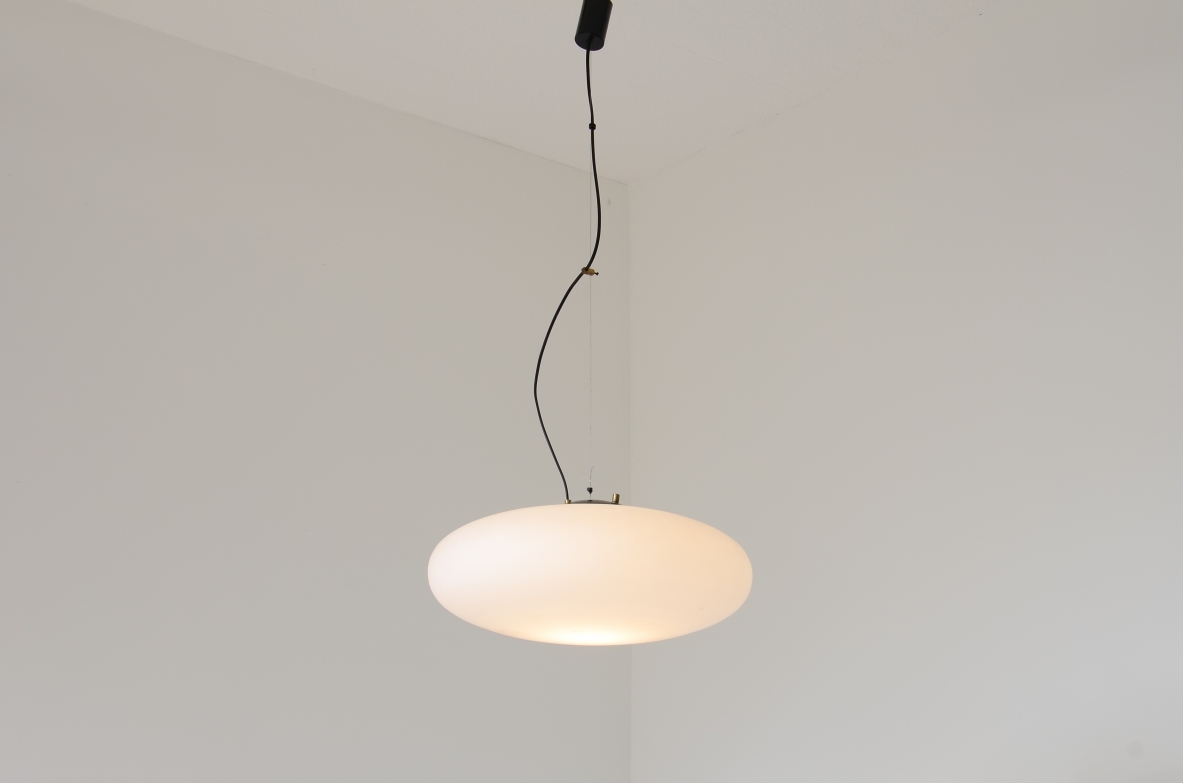 Stilnovo model 1187 pendant lamp, featuring a large ellipsoidal white opaline glass diffuser, black aluminium fitting, brass details and steel suspension cable.