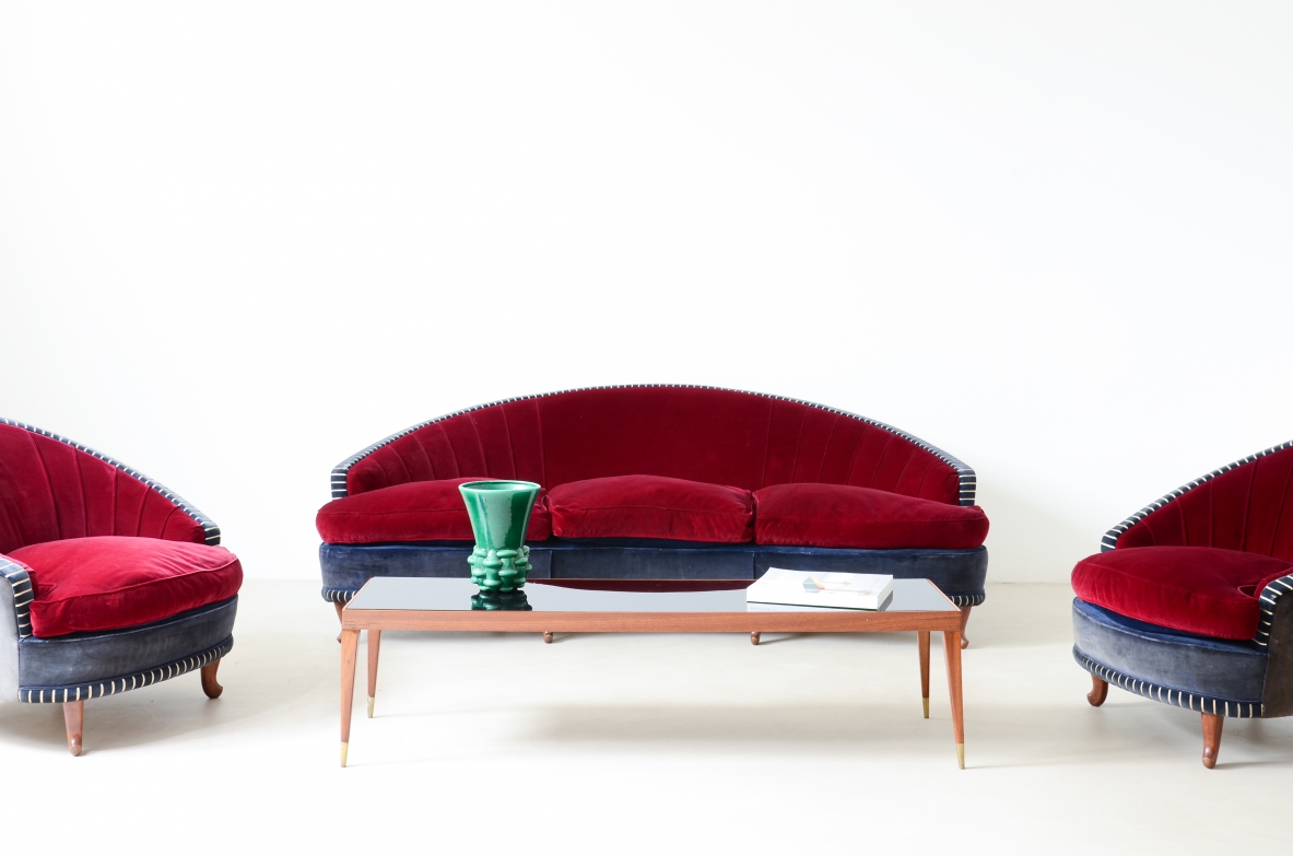 Italian 1940s living room suite with a curved sofa and two matching armchairs, featuring rounded backrests, red and blue velvet upholstery and light wooden legs.
