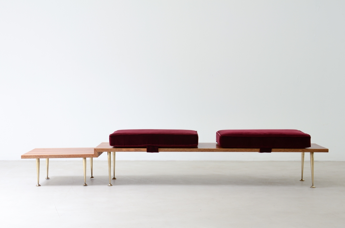 Large shaped wooden bench with eight turned brass feet and velvet-covered cushions.  Italian manufacture from the 1950s
