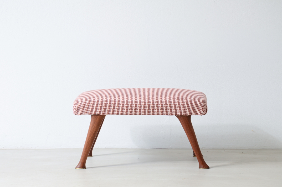 Frontal view of a cherrywood stool with a rectangular seat upholstered in pale pink striped fabric and four outward-angled wooden legs.
