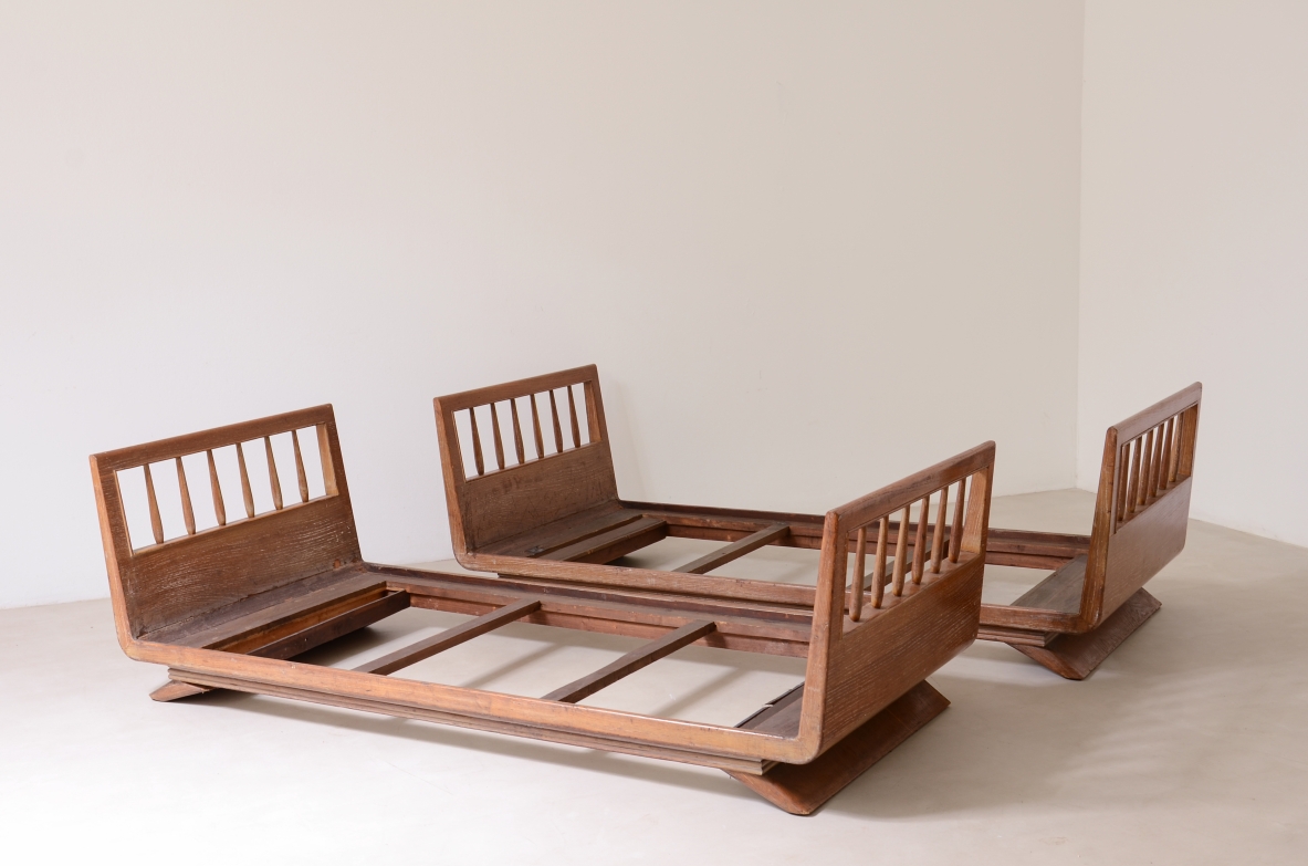 Pair of single beds by Guglielmo Pecorini in textured oak, with rectangular headboards and footboards featuring vertical slats, low wooden frames and shaped bases.