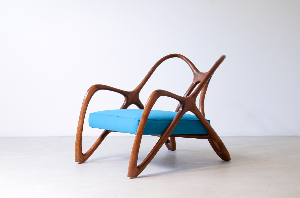 Unique Italian sculptural armchair with an organically curved wooden frame, flowing armrests, angled legs and a bright blue upholstered seat.