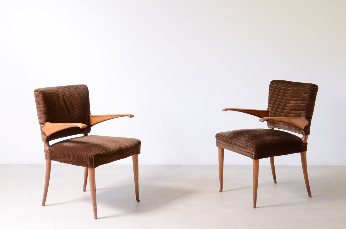 Angled view of two Guglielmo Ulrich armchairs with brown upholstered seats and backs, cantilevered light wood armrests and tapered legs.