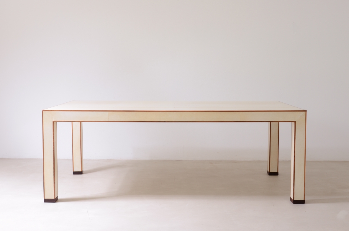 Large rectangular table by Tura Milano, 1990, covered in ivory-colored parchment, with clean geometric lines, double-edged profiles and four square legs with dark wooden tips.