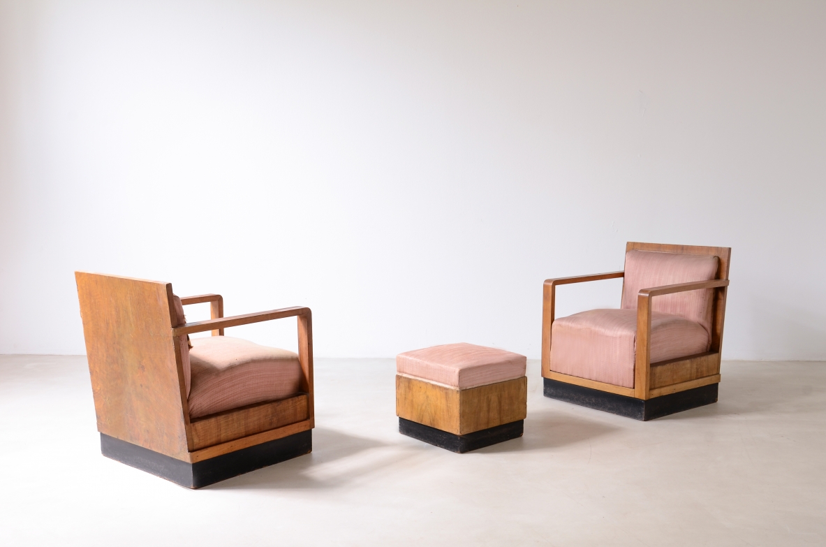Two Italian Rationalist armchairs with geometric wooden frames, dark plinth bases, straight armrests and pink upholstered seats, accompanied by a matching square ottoman.