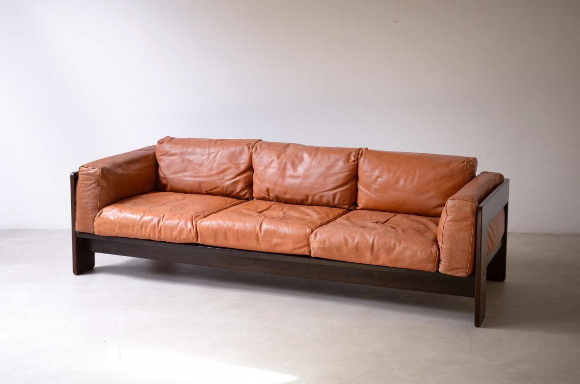 Tobia Scarpa Bastiano three-seater sofa for Gavina, with cognac leather cushions, padded armrests and a geometric dark wooden frame.