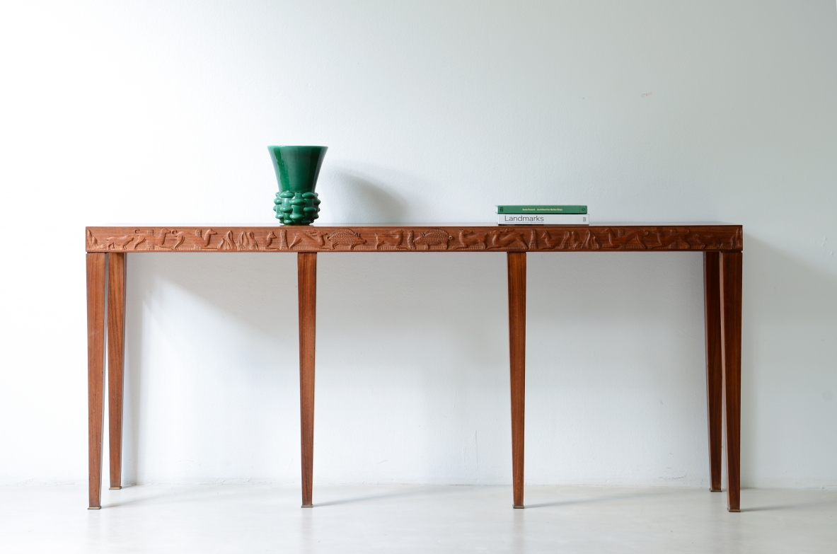 Italian oak console table by Ferdinando Paleari & Co., Lissone, 1935, with finely carved hunting scenes along the apron, six tapered legs and brass feet, front view.